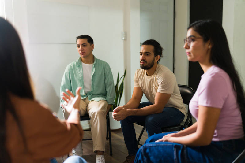 A group of people in a group therapy session, an important part of recovery.