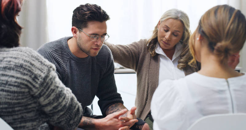 A man in group therapy learning about the difference between physical dependence and addiction.